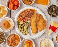 A plate of fried fish surrounded by side dishes and cornbread at Nana Morrison’s Soul Food.