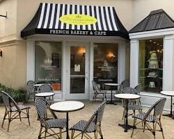 Outdoor café tables beneath the striped awning at Renaissance Pâtisserie.