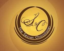 The Secret Chocolatier circular logo on a gold-colored wall.