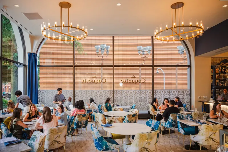 Diners, blue chairs and round chandeliers at Coquette in Charlotte