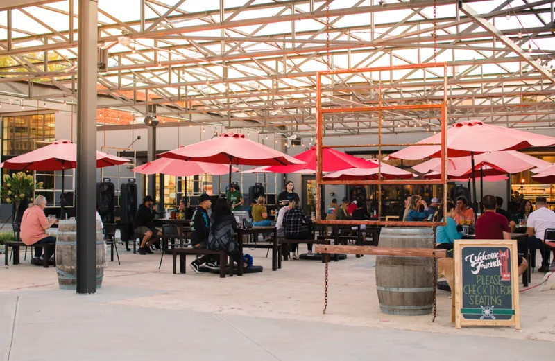 Guests and pink umbrellas on Legion Brewing South Park’s patio in Charlotte